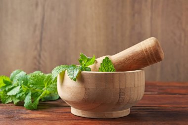 Taze limon merhemi yaprakları, ahşap masada tokmak ve havan topu, yakın plan.