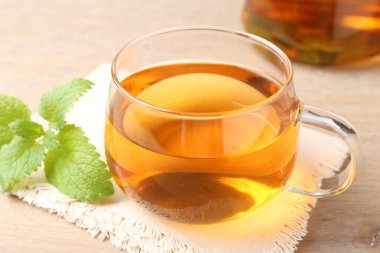 Cam bardakta Aromatik limon merhemi çayı ve masada taze yapraklar, yakın plan.