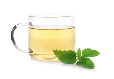 Cam bardakta Aromatik limon merhemi çayı ve beyaz bardakta taze yapraklar.