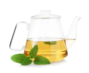 Aromatik limon merhemi çayı, cam çaydanlık ve beyaz yapraklar üzerinde izole edilmiş.