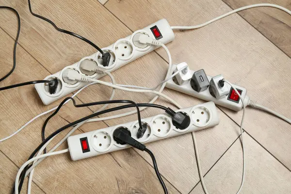 Eklenti güç panoları ahşap zemindeki prizlerle aşırı yüklenmiş, üst görünüm