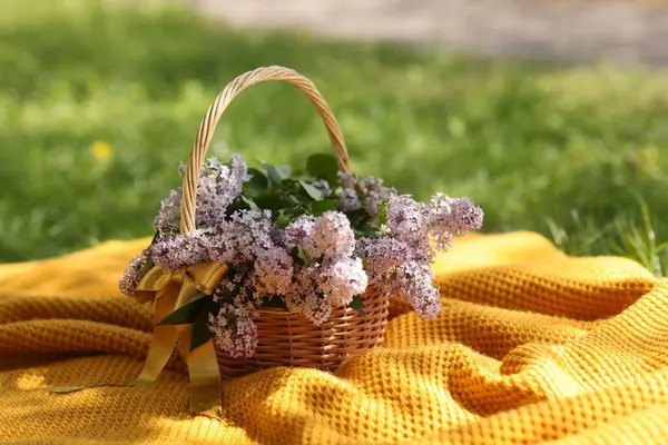 Açık havada üzerinde leylak çiçekleri olan hasır sepet.