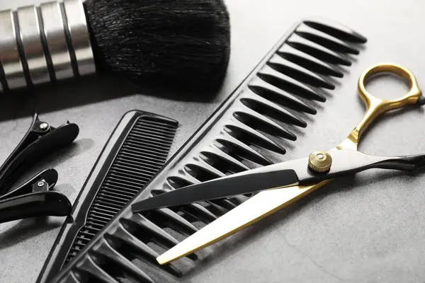 Gri masadaki farklı kuaför aletleri, yakın plan.