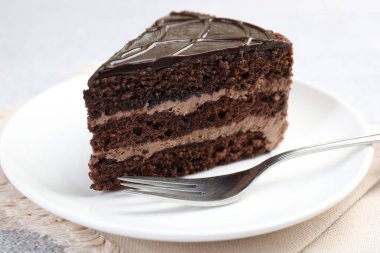 Bir parça lezzetli çikolatalı pasta ve çatal masaya, yakın plan.