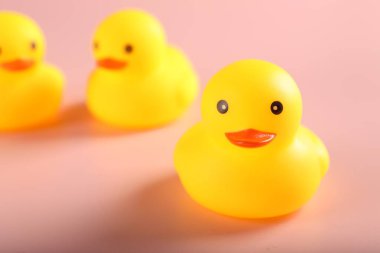 Pembe arka planda üç sevimli lastik ördek, yakın plan.