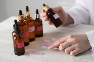 Laboratuvarda beyaz ahşap masada lüks parfüm üreten profesyonel bir parfümcü.