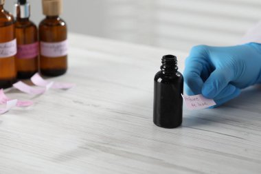 Laboratuvarda beyaz ahşap masada lüks parfüm üreten profesyonel bir parfümcü.