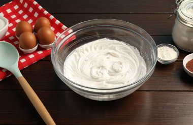 Krem şantili kase ve ahşap masada malzemeler, yakın plan.