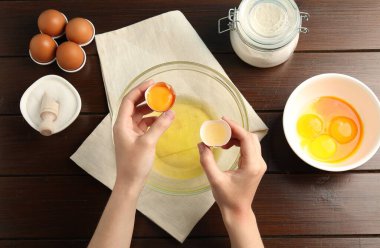 Tahta masada yumurta sarısını beyazdan ayıran kadın.