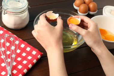 Ahşap masada yumurta sarısını beyazdan ayıran kadın, yakın plan.