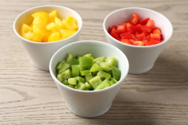 Tahta masadaki kaselerde taze dolmalık biberler, yakın plan.