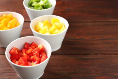 Tahta masadaki kaselerde taze dolmalık biberler, yakın plan. Metin için boşluk