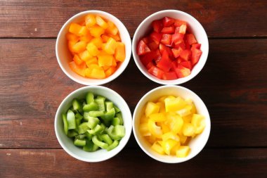 Taze renkli dolmalık biberler ahşap masadaki kaselerde, düz yatıyordu.