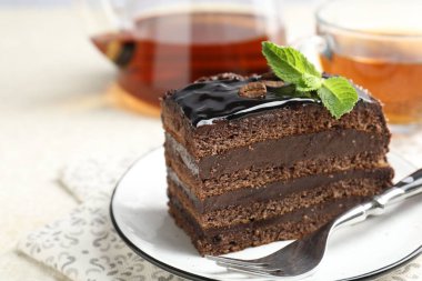 Nane, çatal ve çayla servis edilen bir parça çikolatalı kek, yakın plan. Metin için boşluk