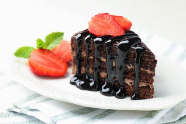 Bir parça çikolatalı kek. Masada çilek var. Yakın plan.