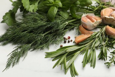 Beyaz masada farklı taze otlar ve baharatlar, yakın plan.