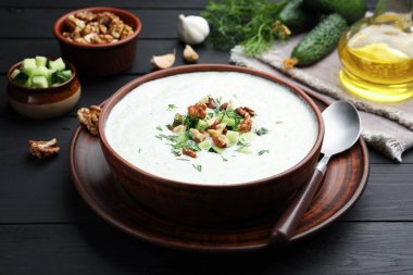 Siyah ahşap masada servis edilen dereotlu ve cevizli lezzetli salatalık çorbası.