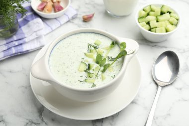 Beyaz mermer masada servis edilen dereotlu ve mikro yeşillikli lezzetli salatalık çorbası.