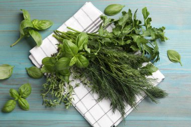 Mavi ahşap masada farklı taze otlar, düz uzanmış.