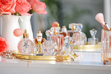 Farklı parfüm şişeleri, aksesuarlar ve çiçekler kapalı salonda.
