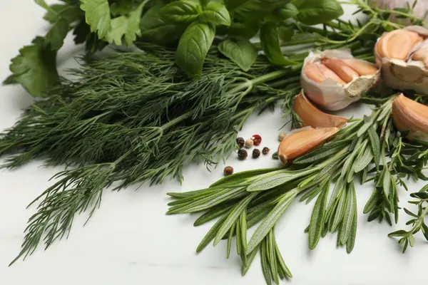 Beyaz masada farklı taze otlar ve baharatlar, yakın plan.