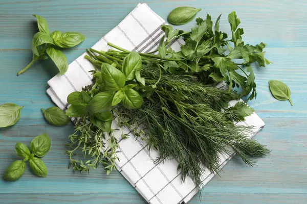 Mavi ahşap masada farklı taze otlar, düz uzanmış.