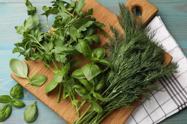 Mavi ahşap masada farklı taze otlar, düz uzanmış.