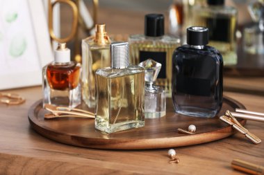 Farklı parfüm şişeleri ve aksesuarlar ahşap masada, yakın plan.