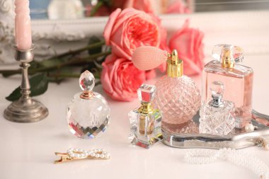 Farklı parfüm şişeleri, aksesuarlar ve çiçekler kapalı salonda.