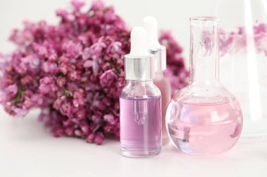 Lüks parfüm yapıyorum. Temel yağlar cam eşyalar ve çiçekler beyaz masada, yakın plan.