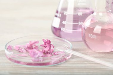 Lüks parfüm yapıyorum. Temel yağlar cam süslemede ve çiçekler beyaz ahşap masada, yakın plan.