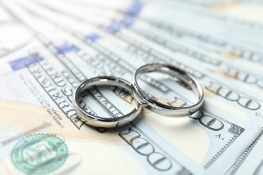 Dolar banknotları üzerinde iki gümüş alyans, yakın plan.