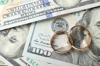 Dolar banknotları üzerinde iki altın alyans, üst manzara.