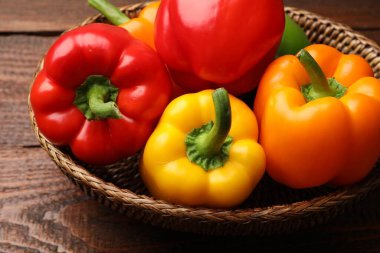 Taze renkli dolmalık biberler hasır sepetin içinde ahşap masanın üstünde, yakın plan.