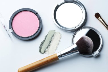 Beyaz arka planda farklı makyaj ürünleri ve fırçalar, düz konum