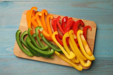 Mavi ahşap masada renkli dolmalık biberler, üst manzara.