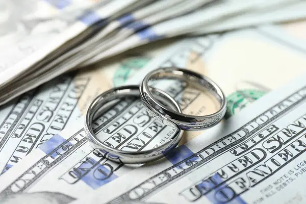 Dolar banknotları üzerinde iki gümüş alyans, yakın plan.