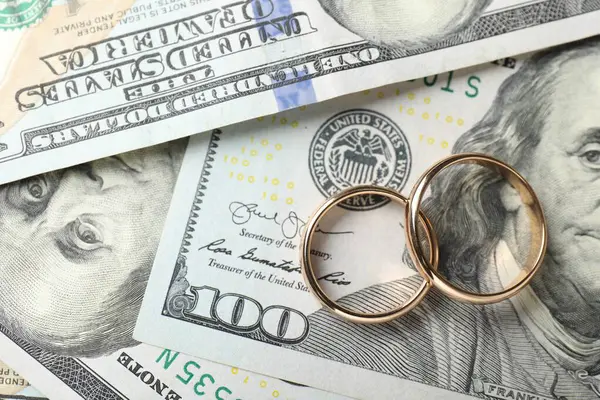 Dolar banknotları üzerinde iki altın alyans, üst manzara.