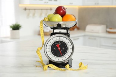 Meyveli mutfak pulları ve kapalı alandaki hafif mermer masada mezura.