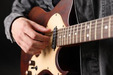 Siyah arkaplanda gitar çalan adam, yakın plan