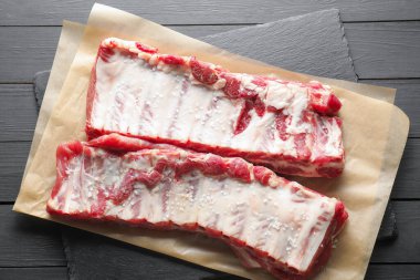 Siyah ahşap masada deniz tuzu ve çiğ domuz pirzolası.