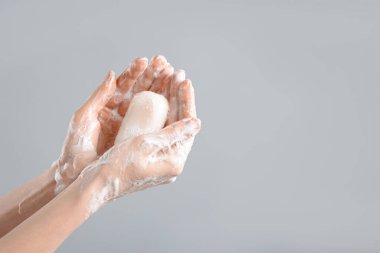 Açık gri arka planda ellerini sabunla yıkayan kadın, yakın plan. Metin için boşluk
