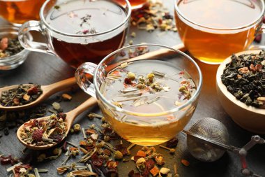 Siyah masada farklı bitki çayları ve kuru yapraklar, yakın plan.