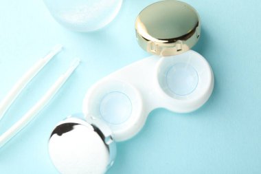 Açık turkuaz arka planda kontak lensler ve cımbızlar düz konum