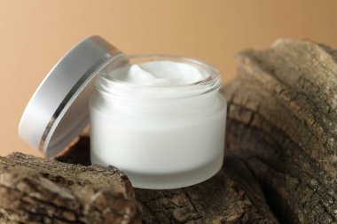 Bej arka planda bir kavanoz vücut kremi, yakın plan.