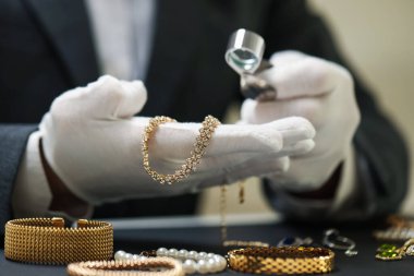 Masadaki lüks mücevherleri değerlendiren eksper, yakın plan.