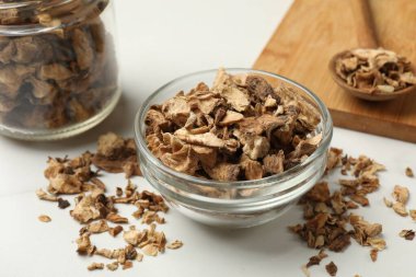 Kuru hindiba kökleri kasede, kavanoz ve kaşık beyaz masada, yakın plan.