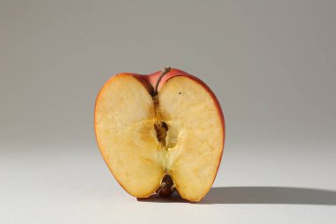 Açık gri arkaplanda hasarlı elmanın yarısı