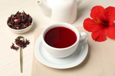 Fincanda leziz amber çayı, çaydanlık, kuru roselle sepals ve açık ahşap masada çiçek, yakın plan.