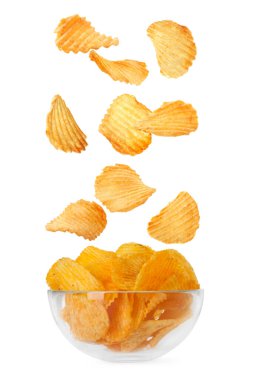 Lezzetli patates cipsleri beyaz arka planda kaseye düşüyor.